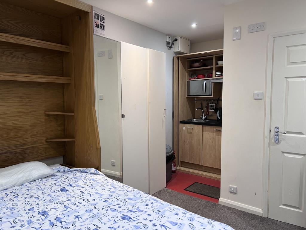 Lot: 23 - SIX-BEDROOM GUEST HOUSE - Studio room showing bed and kitchenette